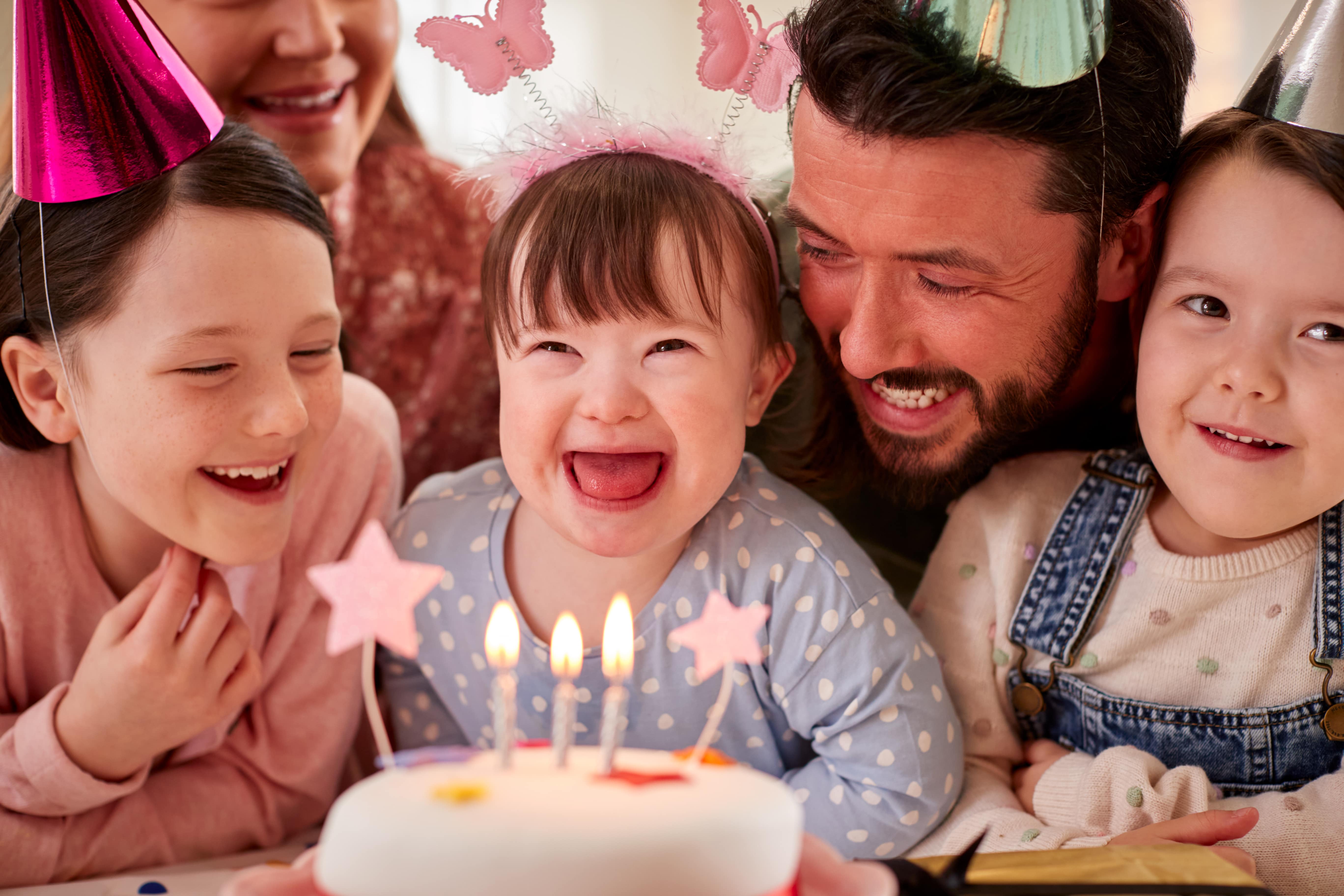 Family with down syndrome daughter celebrating first birthday party at home together